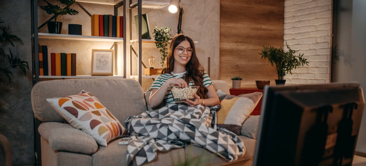 Mujer comiendo palomitas y viendo una serie | Getty Images / PhotoAttractive
